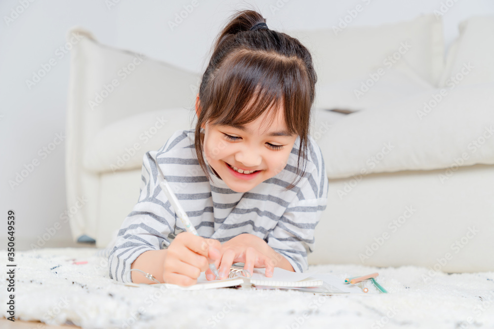 Asian little girl writing on the carpet