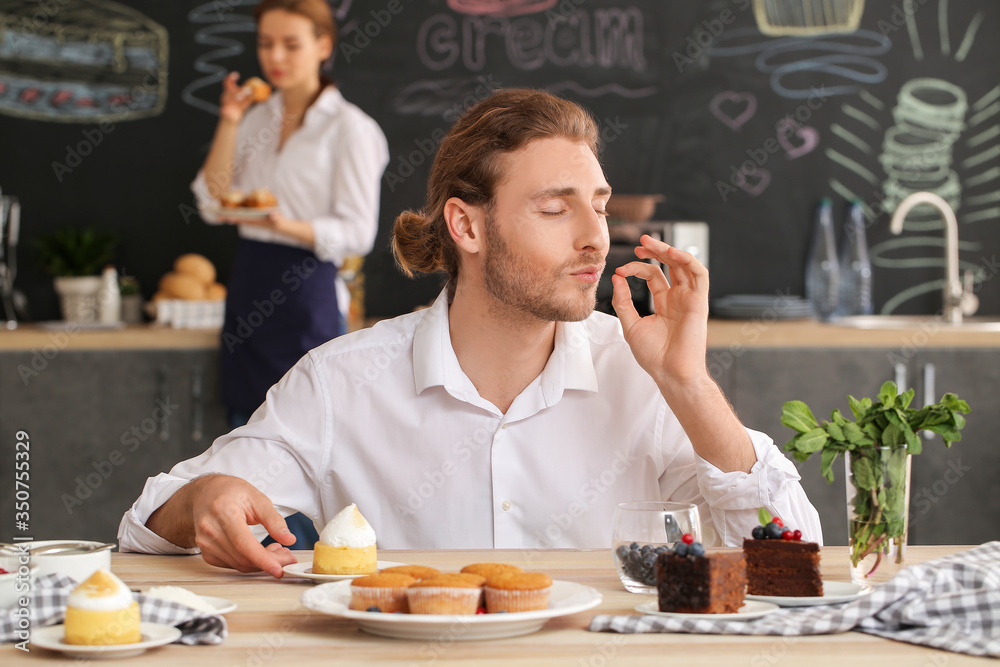 Male confectioner with tasty desserts in kitchen