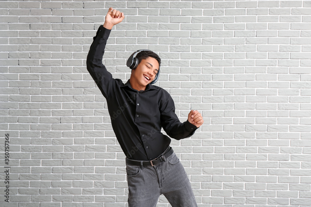 African-American teenager dancing and listening to music against brick background