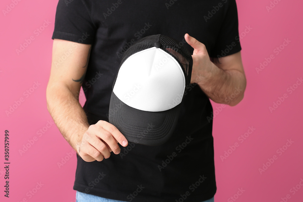 Handsome man with stylish cap on color background