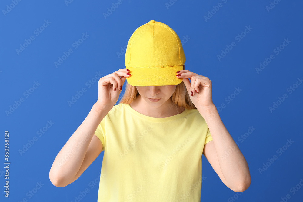 Beautiful young woman in stylish cap on color background