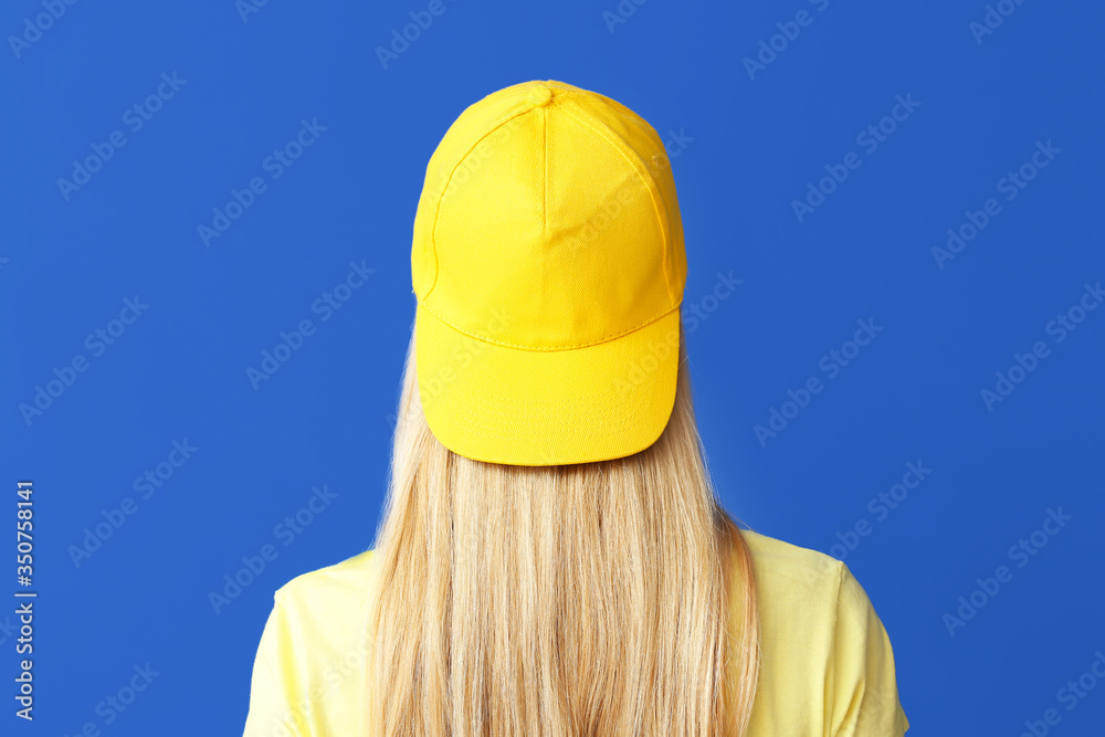 Beautiful young woman in stylish cap on color background