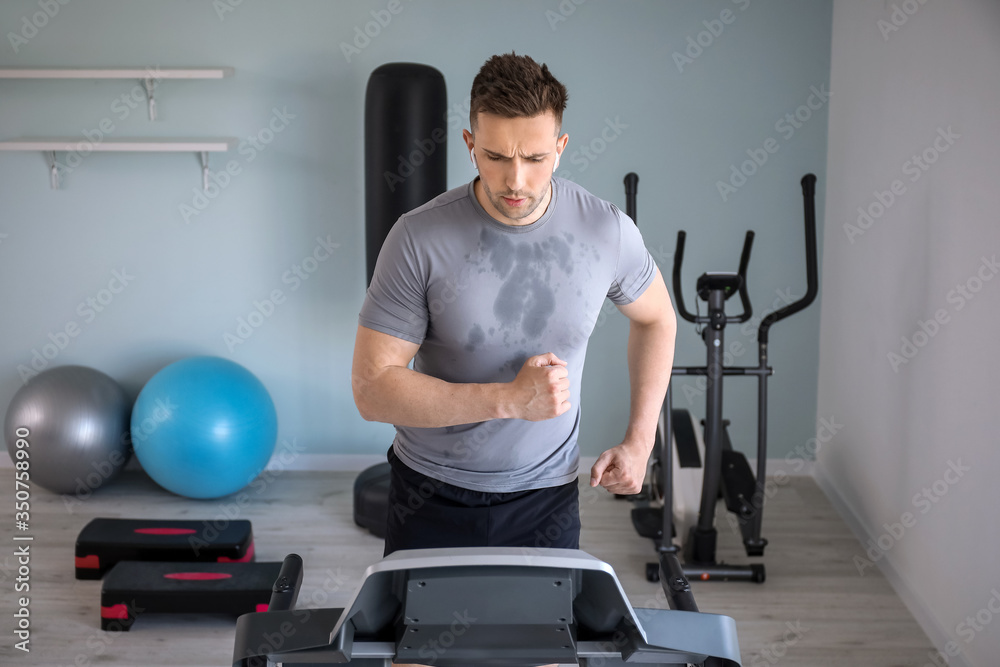 Young man training on treadmill in gym