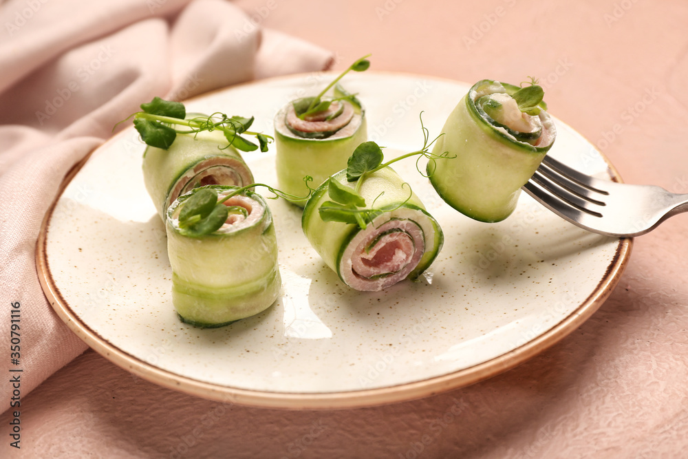 Plate with tasty cucumber rolls on color background