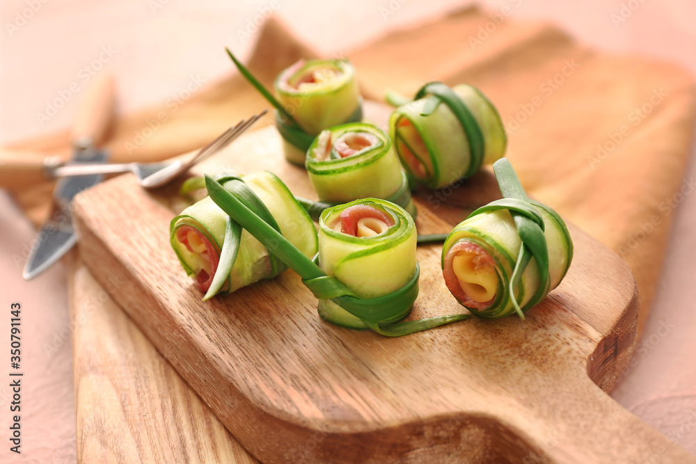 Boards with tasty cucumber rolls on table