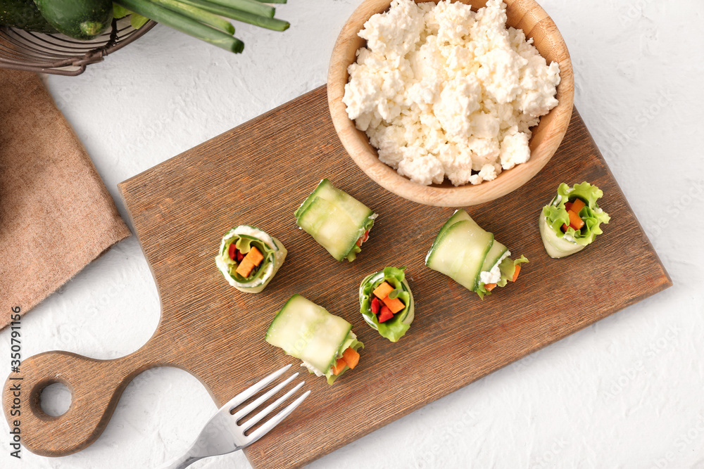 Board with tasty cucumber rolls on white background