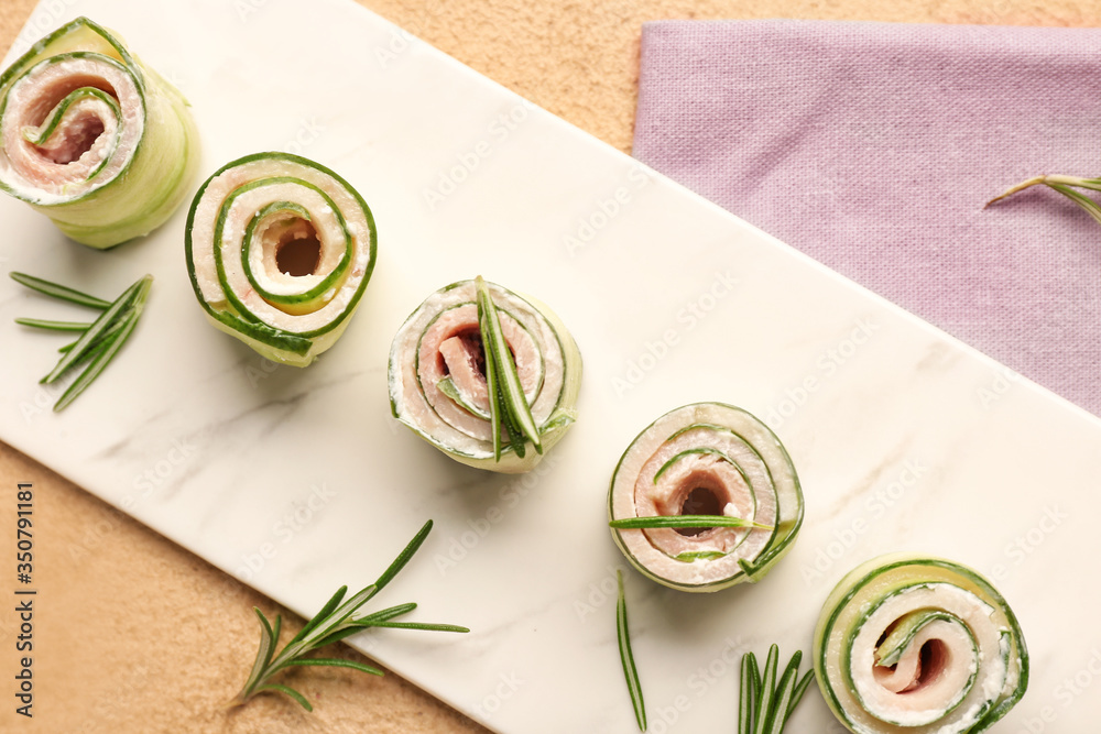 Board with tasty cucumber rolls on table