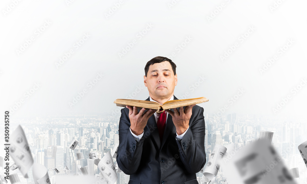 Serious businessman holding open old book