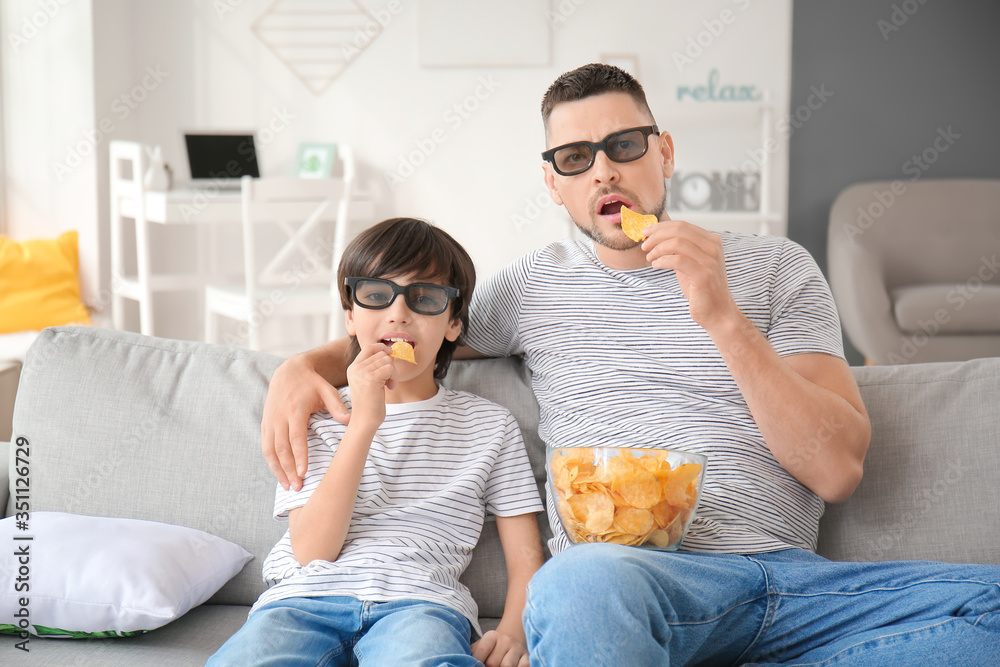 Father and little son watching movie at home