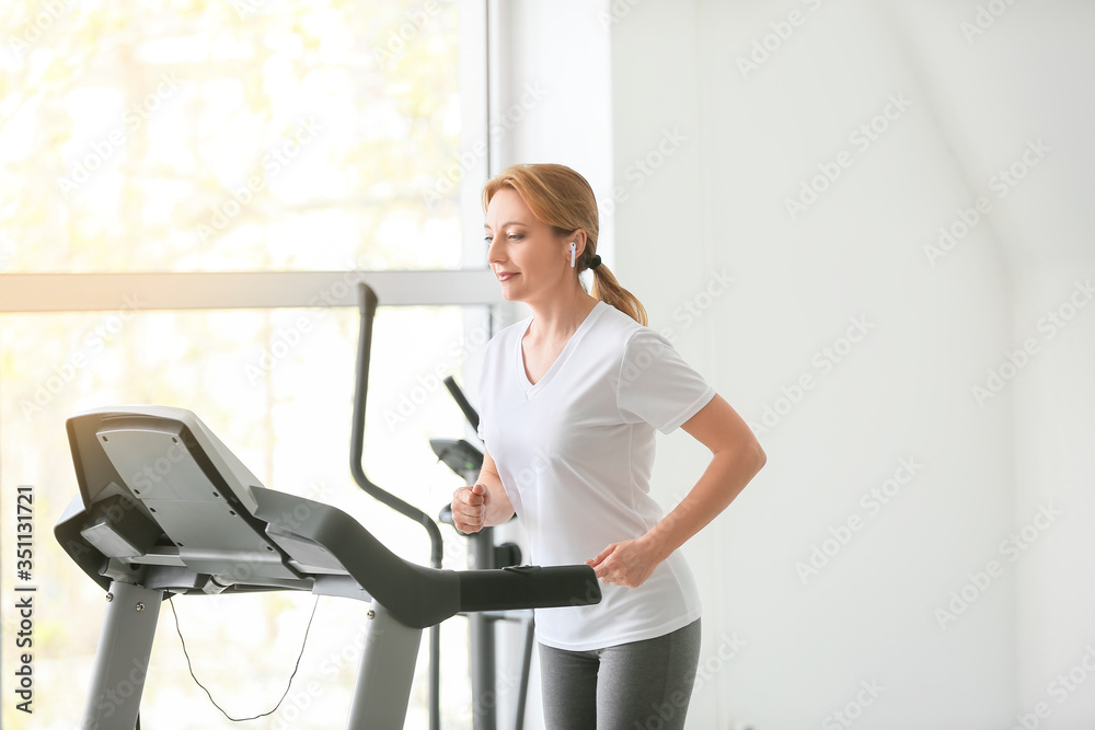 Sporty woman training on treadmill in gym