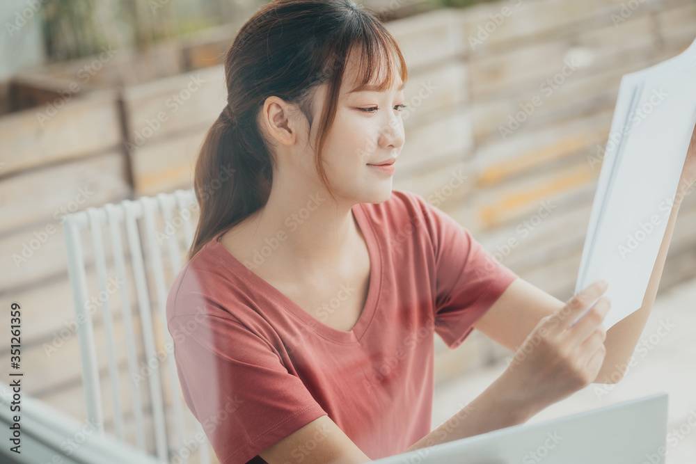 亚洲女性早上在阳台上阅读文件