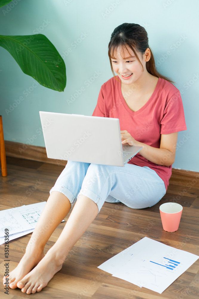 Asian woman sitting on the floor while she working from home