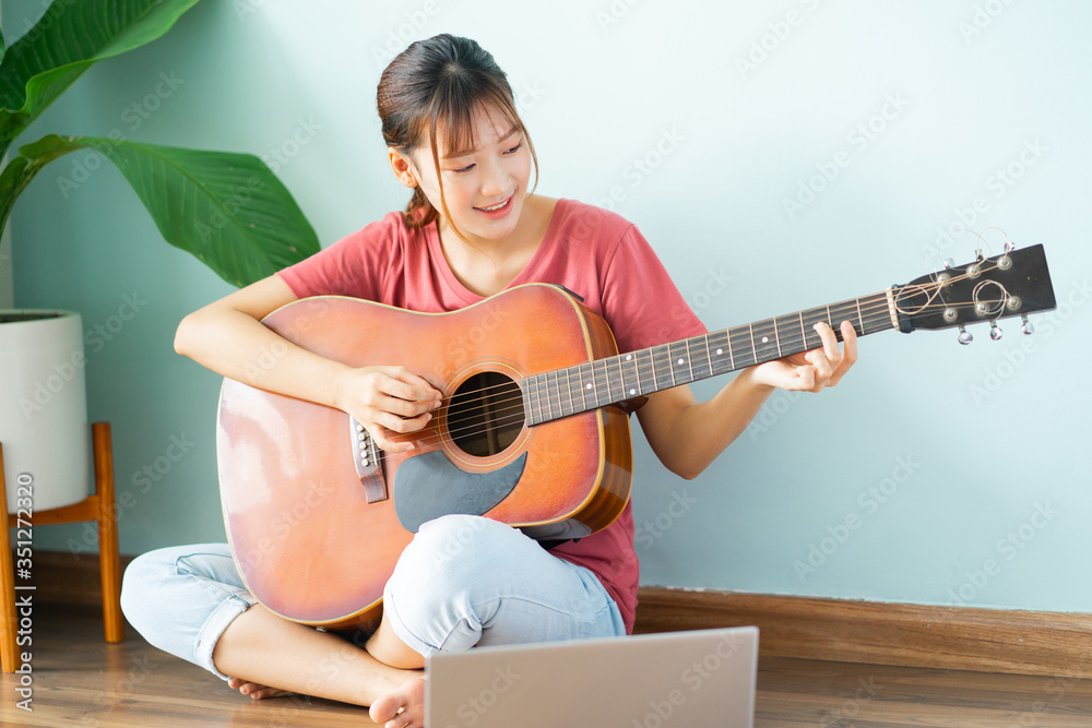 在家学习吉他的亚洲年轻女性