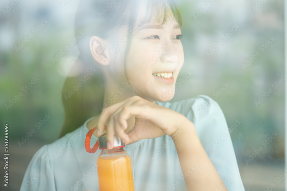 Young Asian woman drink orange juice beside the window at morning