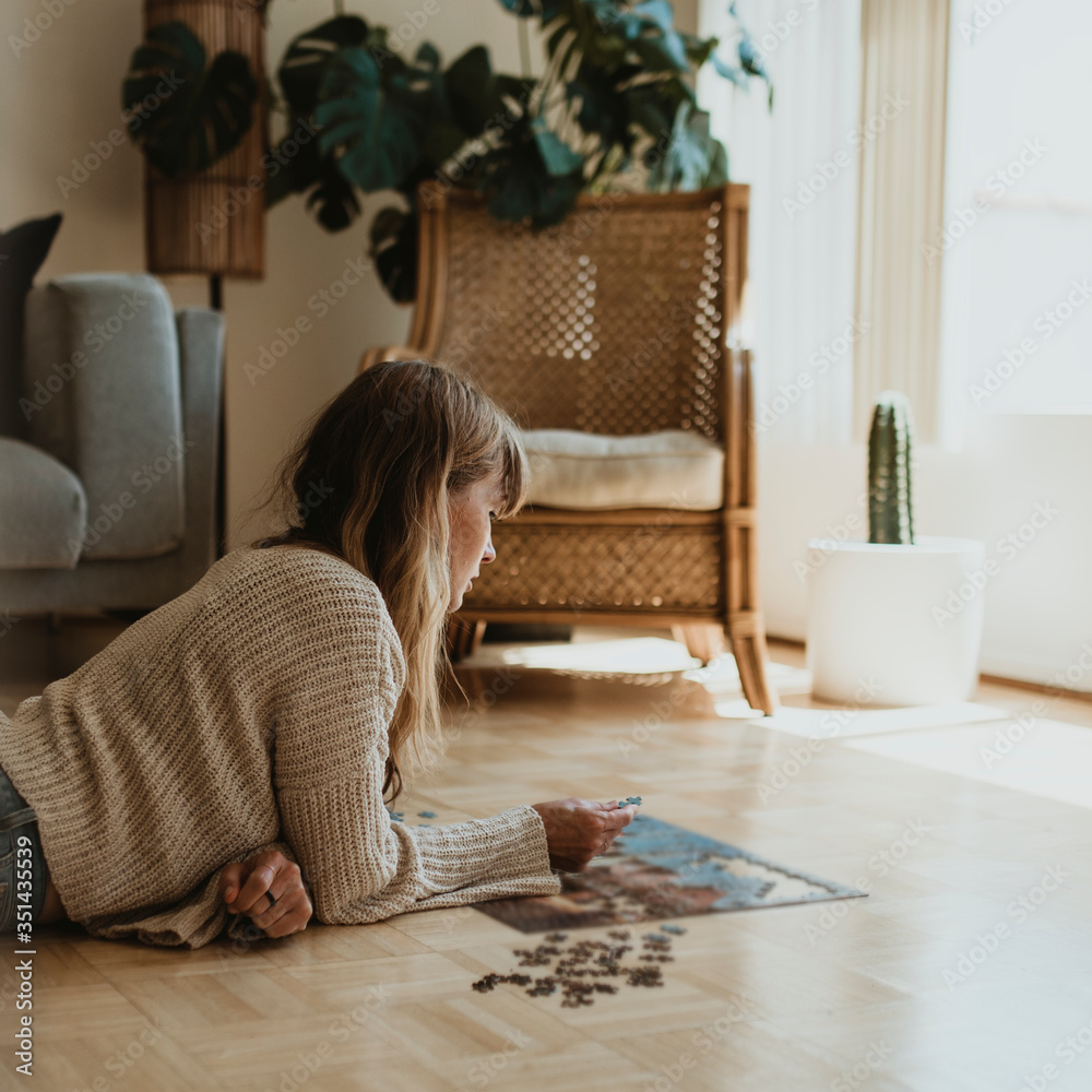 Woman putting together a jigsaw puzzle during self quarantine