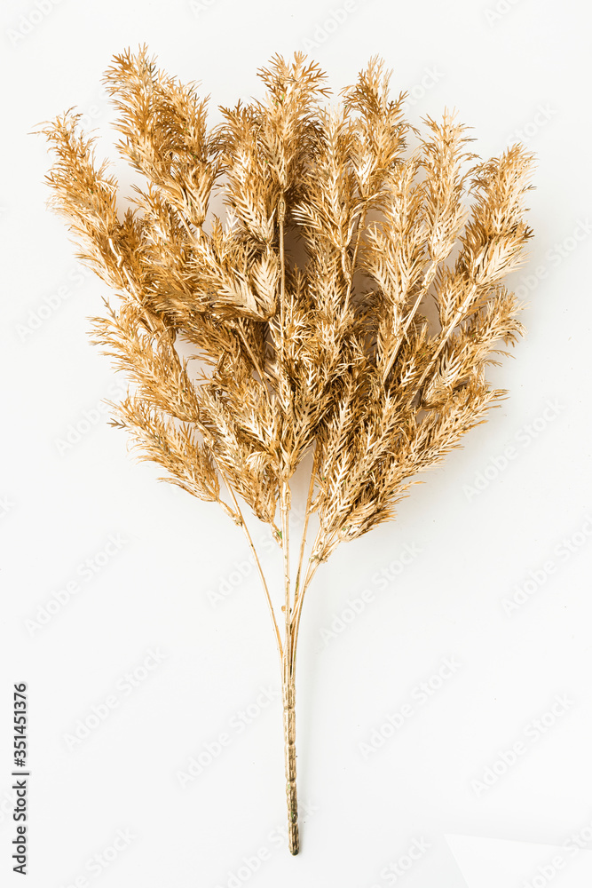 Artificial gold fern leaves on an off white background