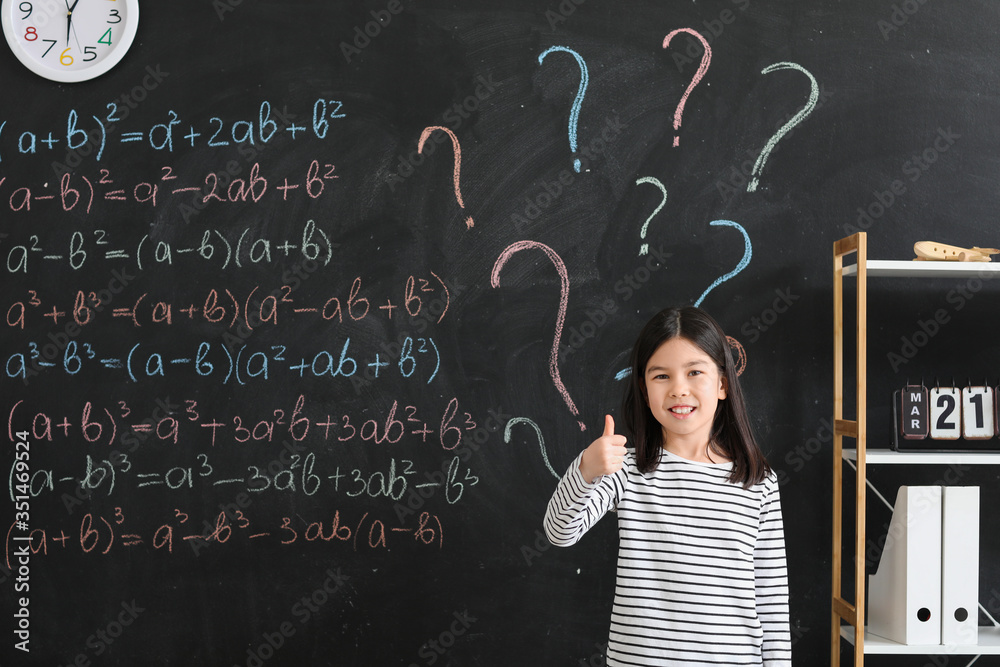 Little girl near school blackboard in classroom