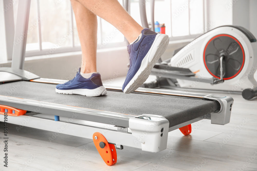 Young man training on treadmill in gym