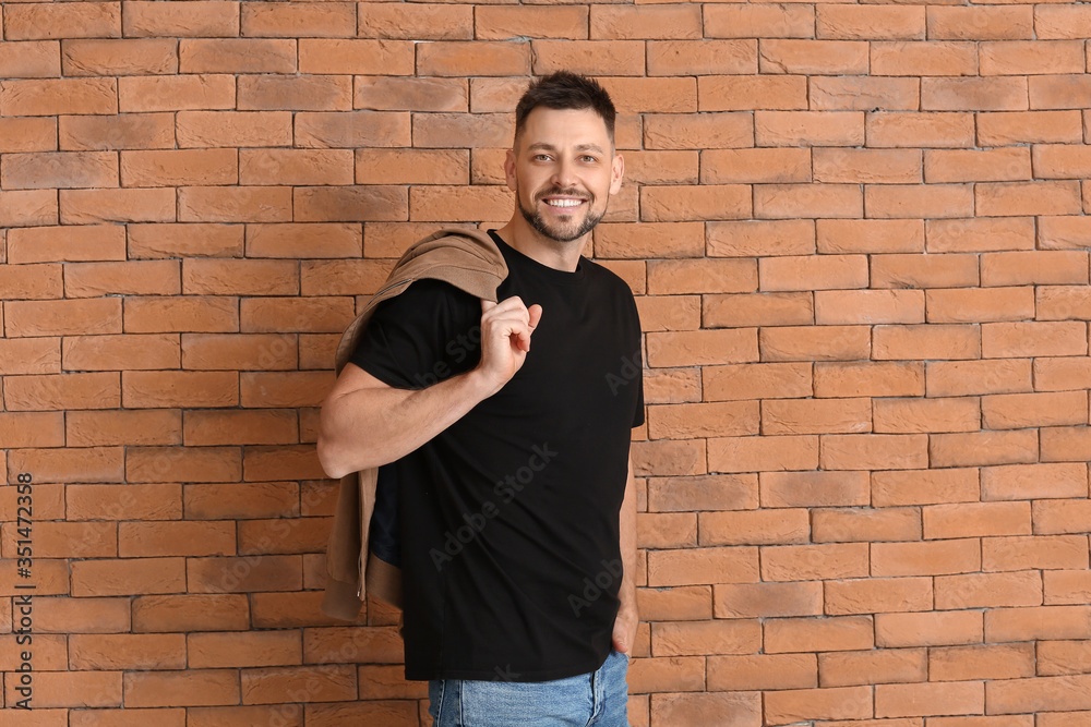 Man in stylish t-shirt near brick wall