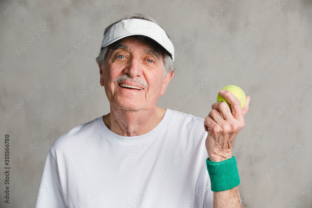 Cheerful senior man with a tennis ball