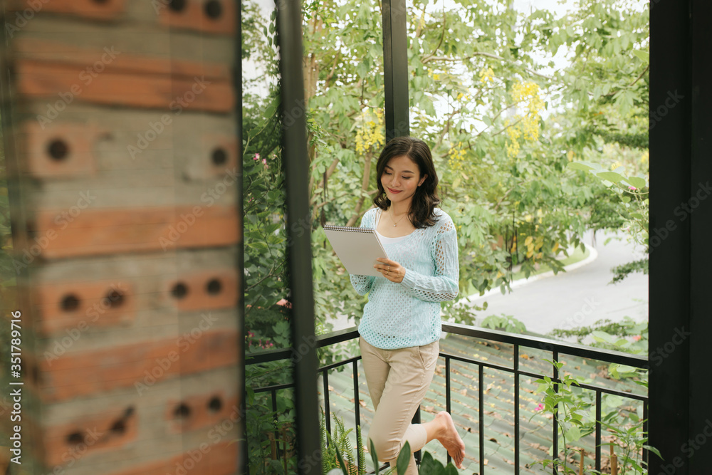 Portrait of happy asian woman standing with notepad