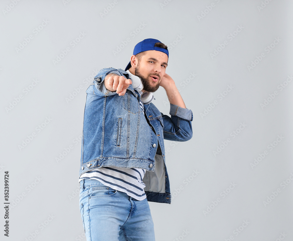 Handsome young man dancing against light background