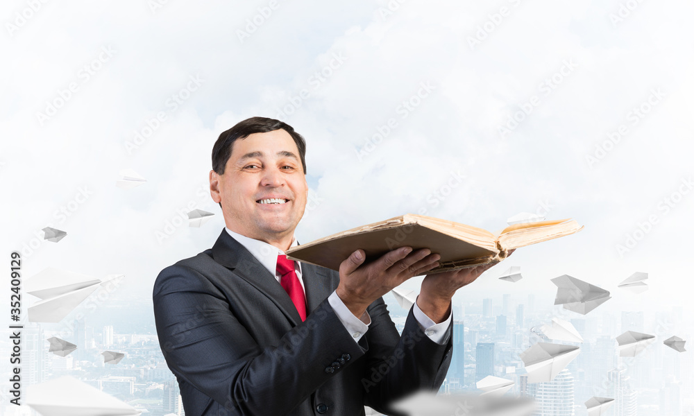 Happy businessman holding open old book