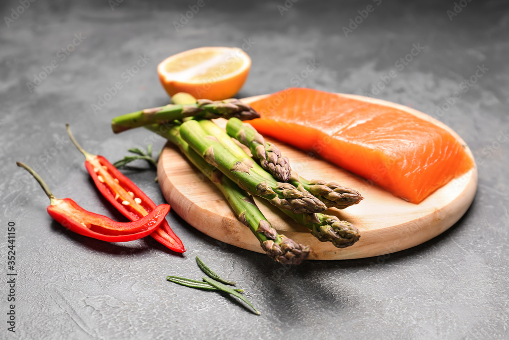 Asparagus with salmon, lemon and chili pepper on dark background