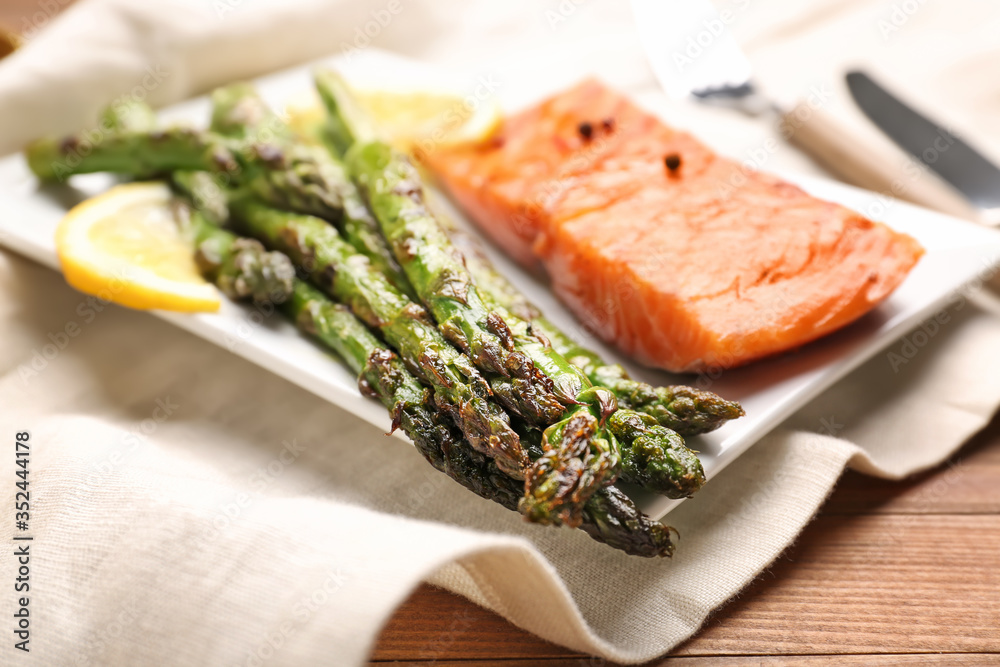 Cooked asparagus with salmon and lemon on plate