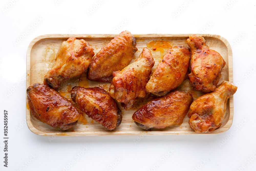 Baked chicken wings in a wooden plate on a white table