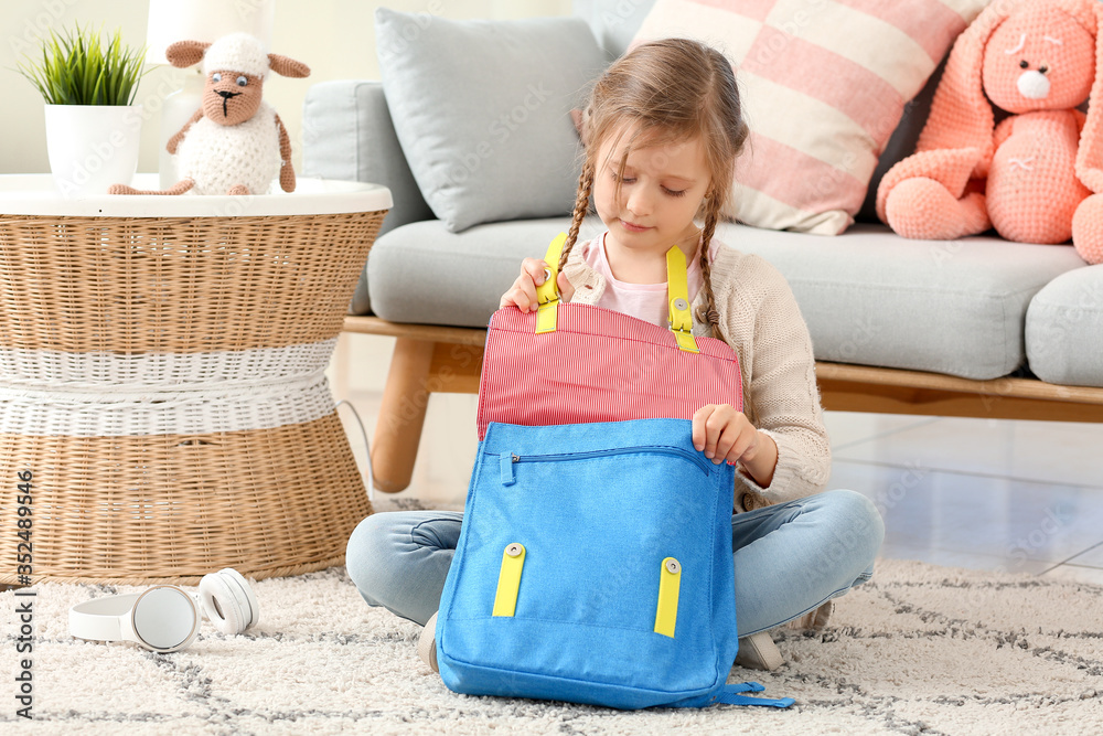 Cute little girl packing schoolbag at home