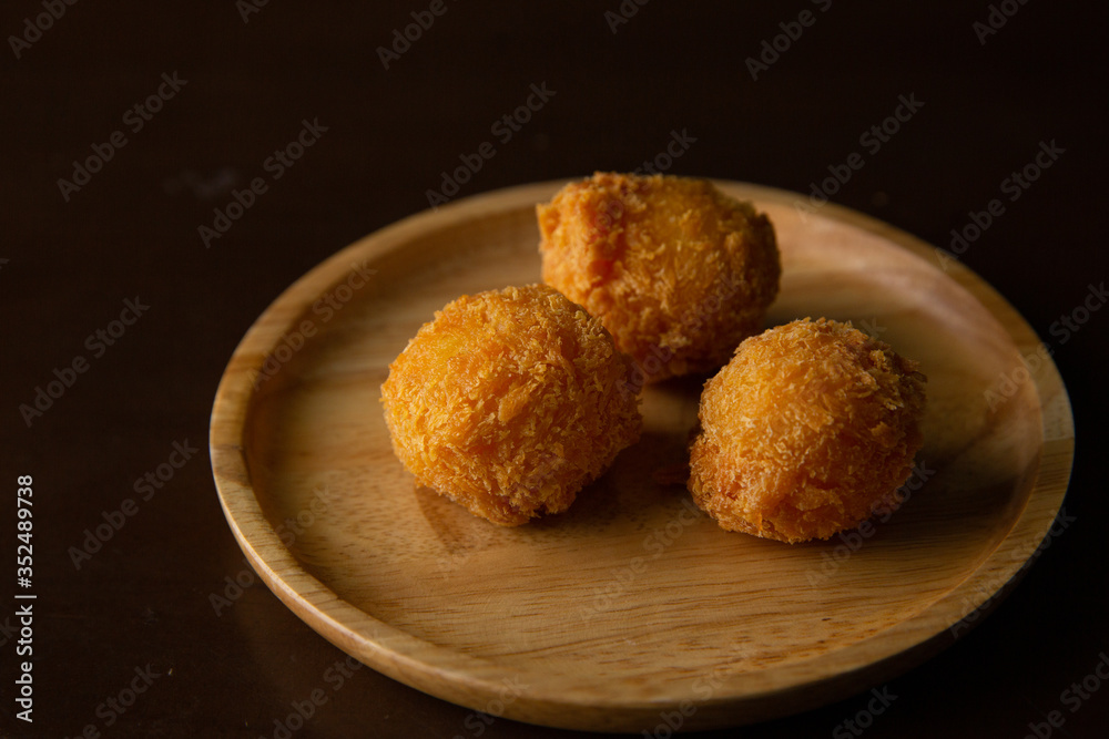 Cheese ball on a wooden plate on a black background