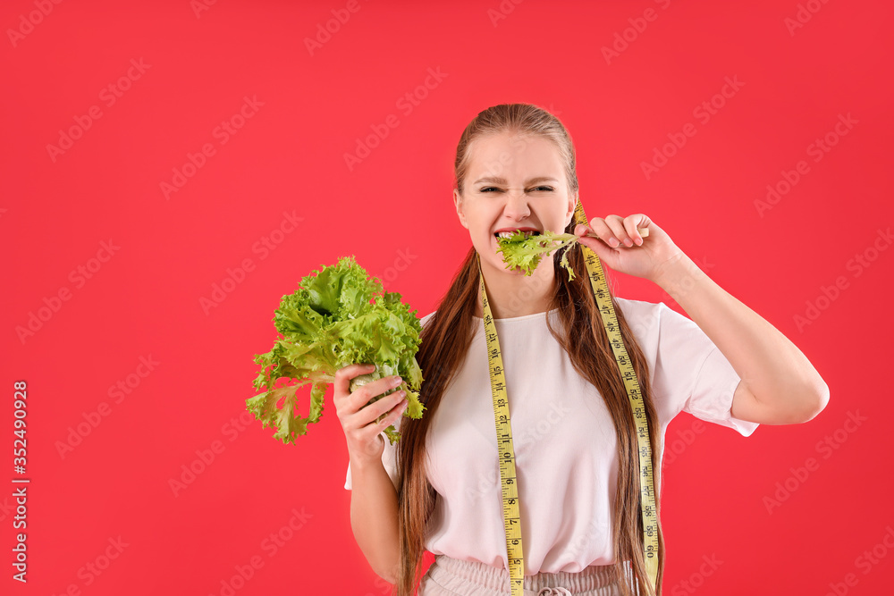 年轻女子，带着生菜和彩色背景的卷尺。饮食概念