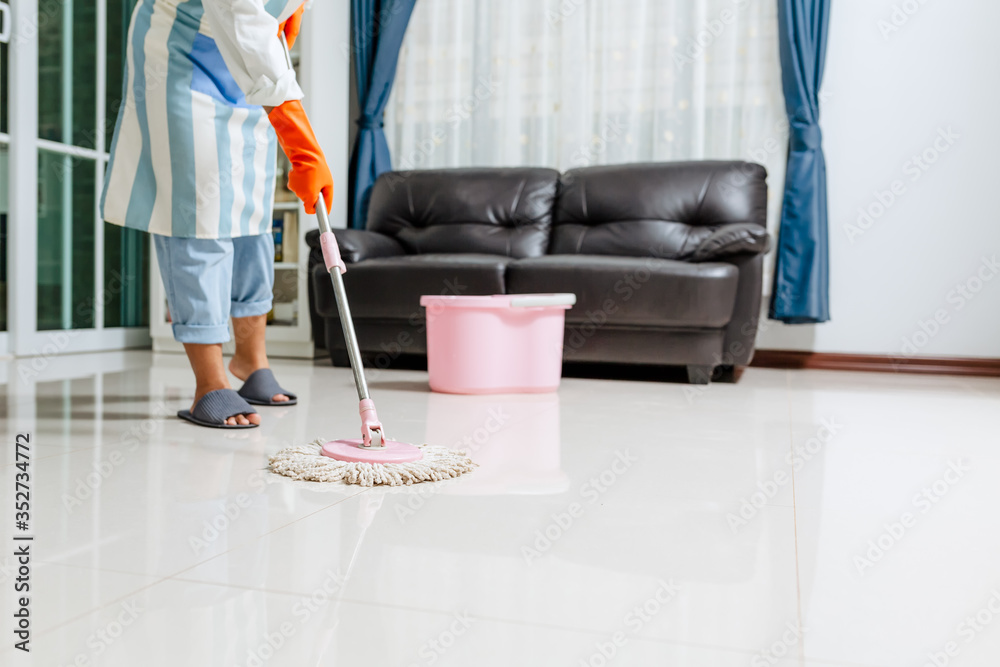 Asian beautiful young woman in protective gloves using a flat wet-mop while cleaning floor in the ho