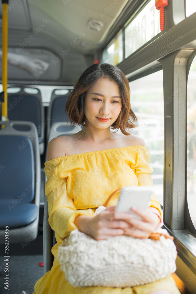 Beautiful woman using mobile phone when sitting on bus/ public transportation.