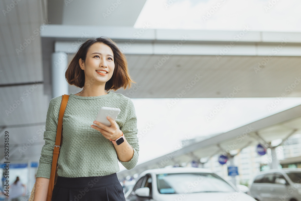 年轻的女商人站在外面用电话检查航班。