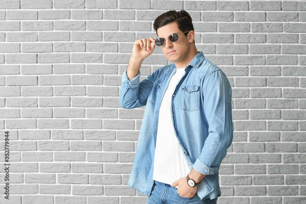 Portrait of handsome stylish man on brick background