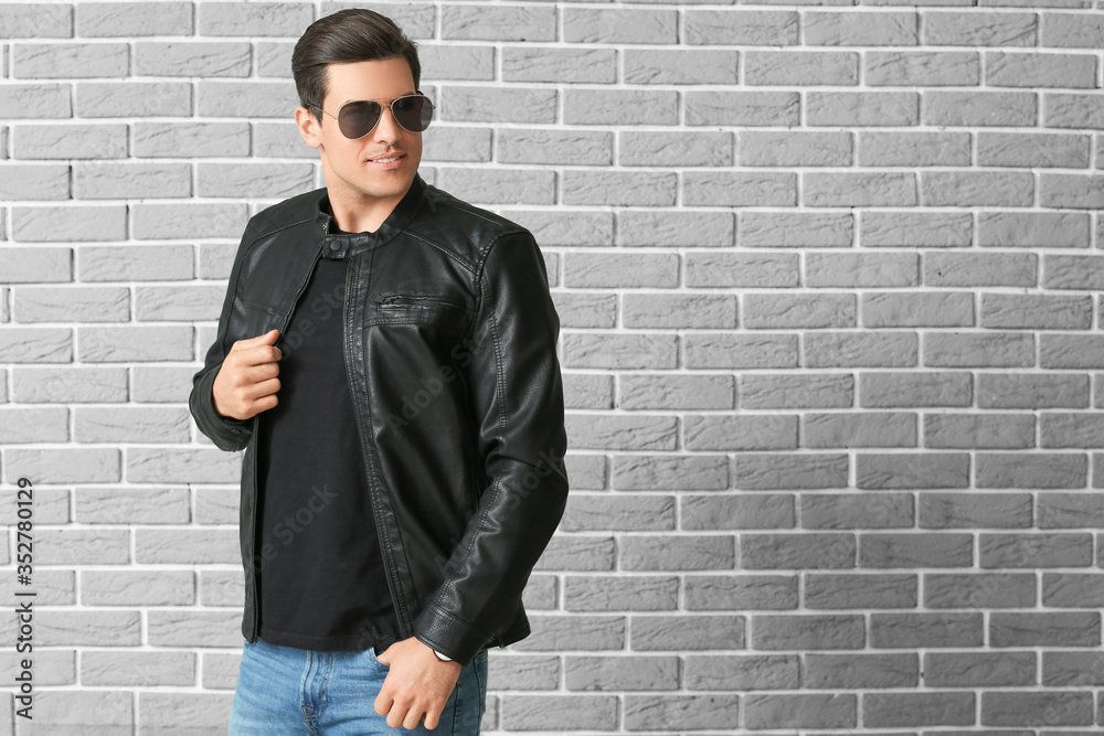 Man in stylish clothes on brick background