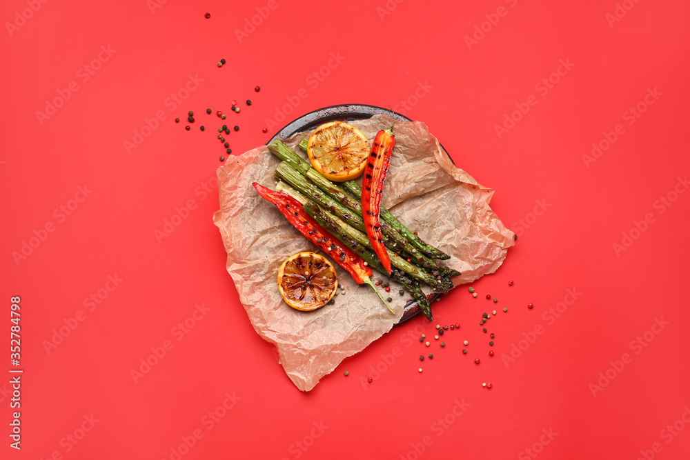 Cooked asparagus with chili pepper and lemon on color background