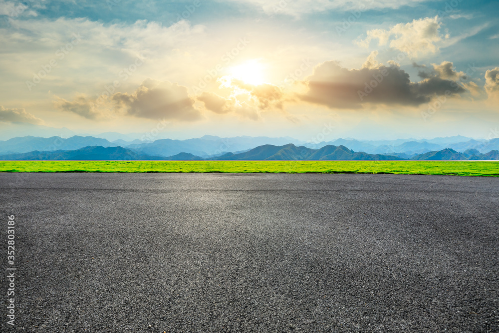 Empty asphalt road and green mountain landscape at sunset.