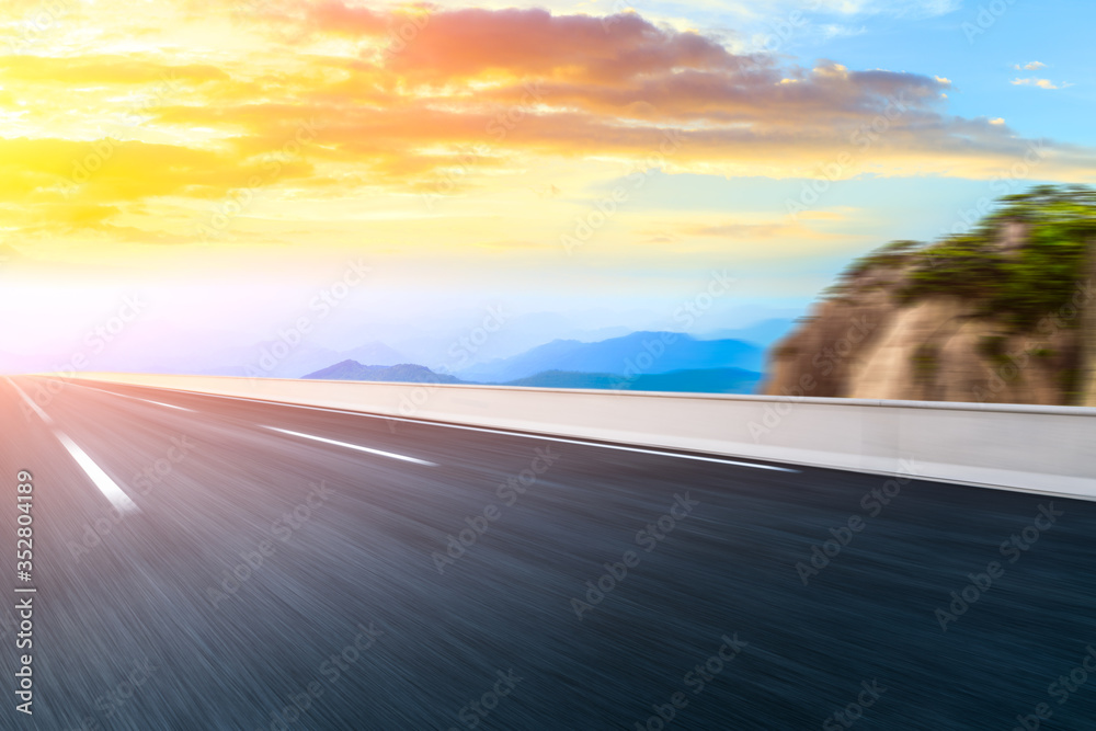 Motion blurred mountain road,asphalt roads and mountains with sky clouds at sunset.