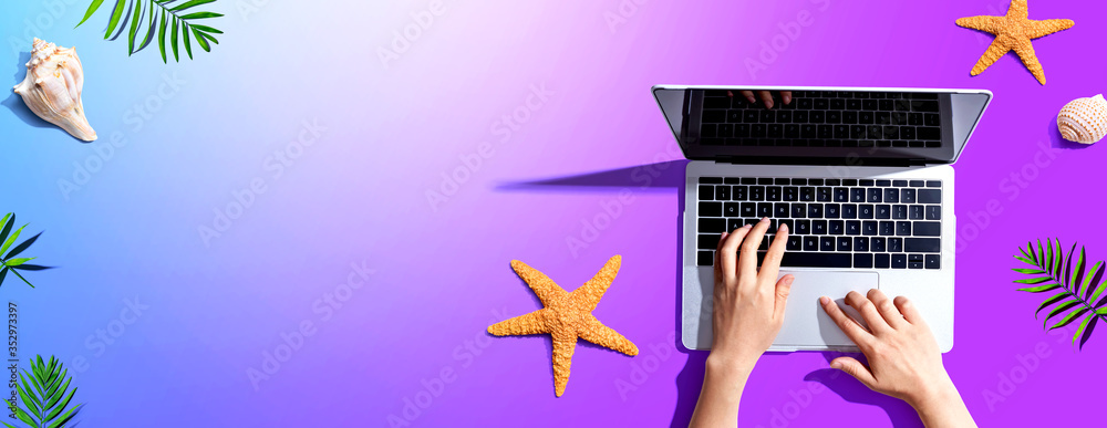 Person using a laptop computer with summer theme objects - flat lay