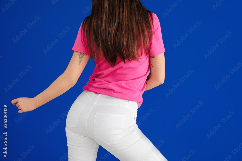 Beautiful young woman dancing against color wall