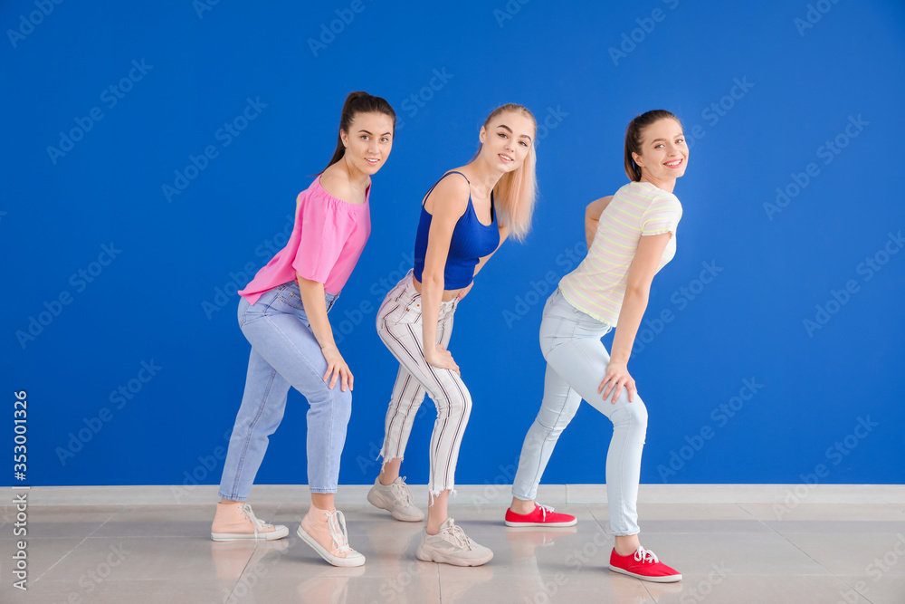 Beautiful young women dancing against color wall