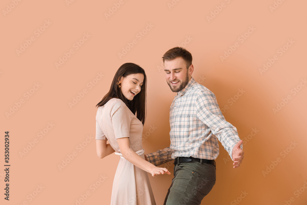 Happy young couple dancing against color background