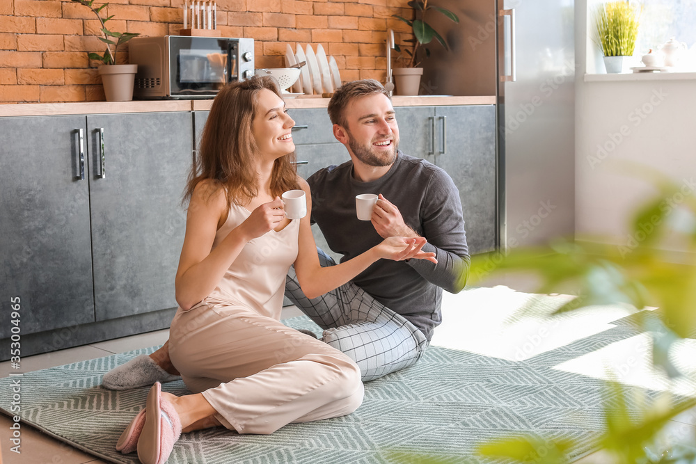 Morning of happy young couple drinking coffee in kitchen