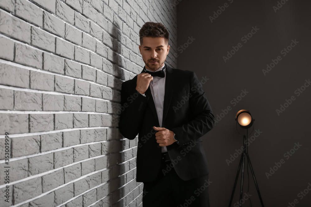 Handsome young man in elegant suit near brick wall