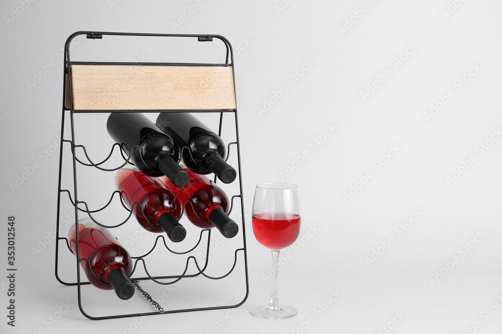 Holder with bottles of wine on grey background