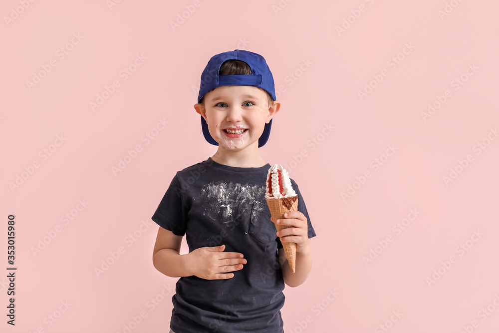 Little boy in dirty clothes eating ice-cream on color background