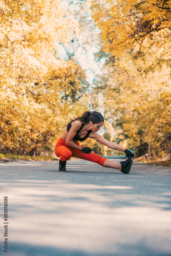  Female athlete preparing for jogging outdoors. Young woman doing stretching exercises.